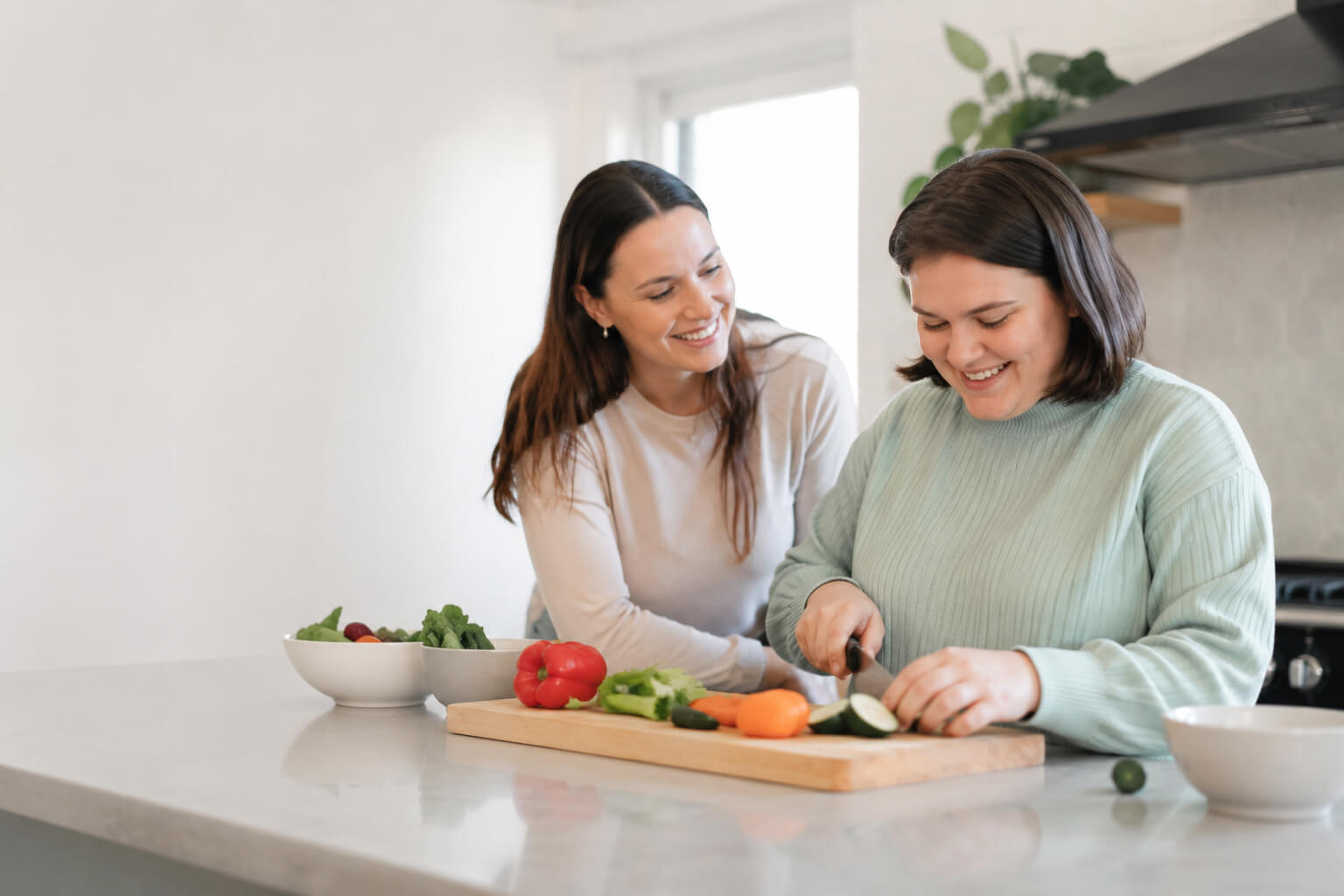 Two people preparing vegetables together in a bright kitchen.